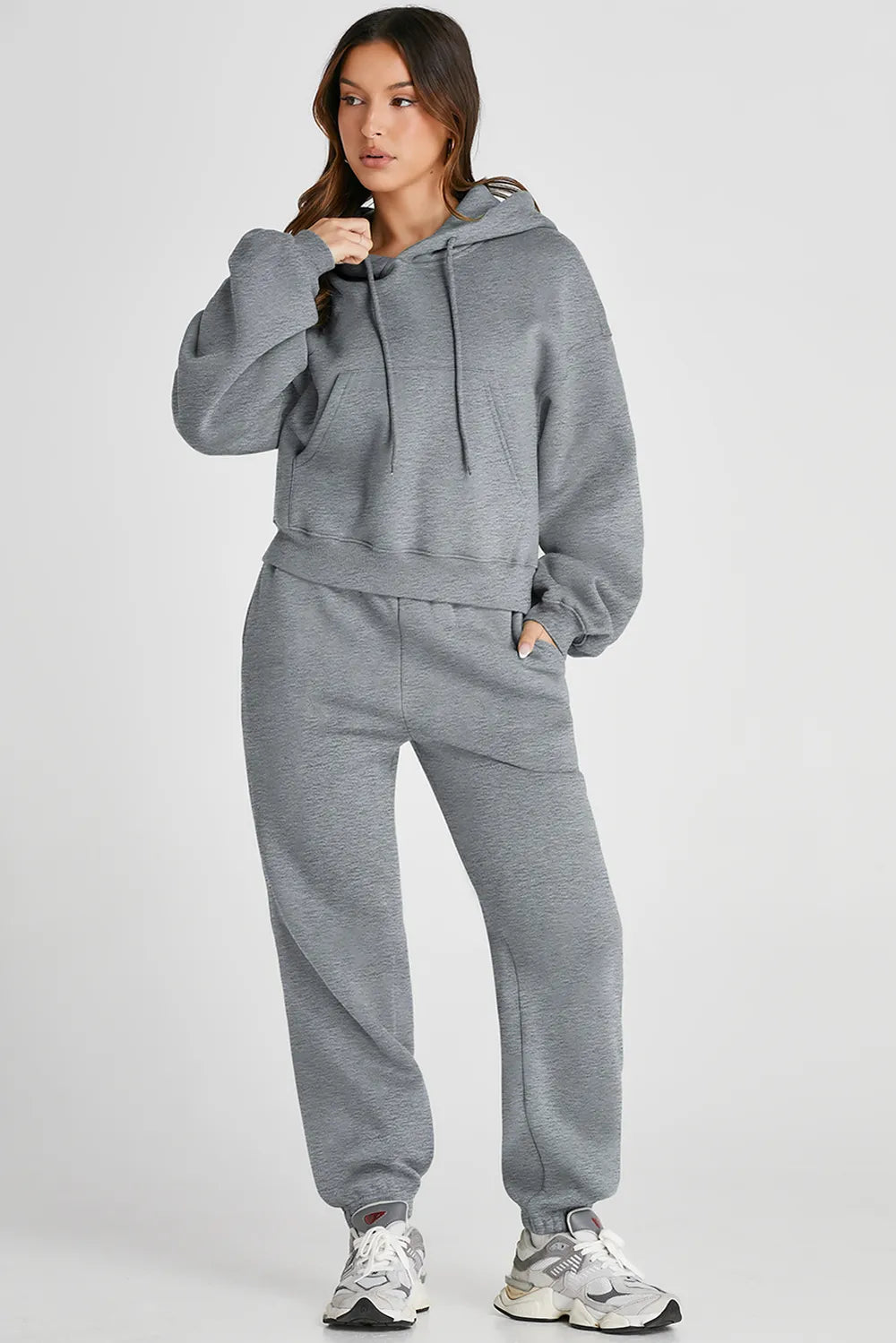 Woman wearing Dropped Shoulder Hooded Top and Pants Active Set in gray with drawstring and pockets, perfect for casual or active wear.
