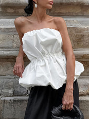 Woman wearing a white Ruched Bubble Hem Tube Top with elegant ruched bodice and voluminous bubble hem.