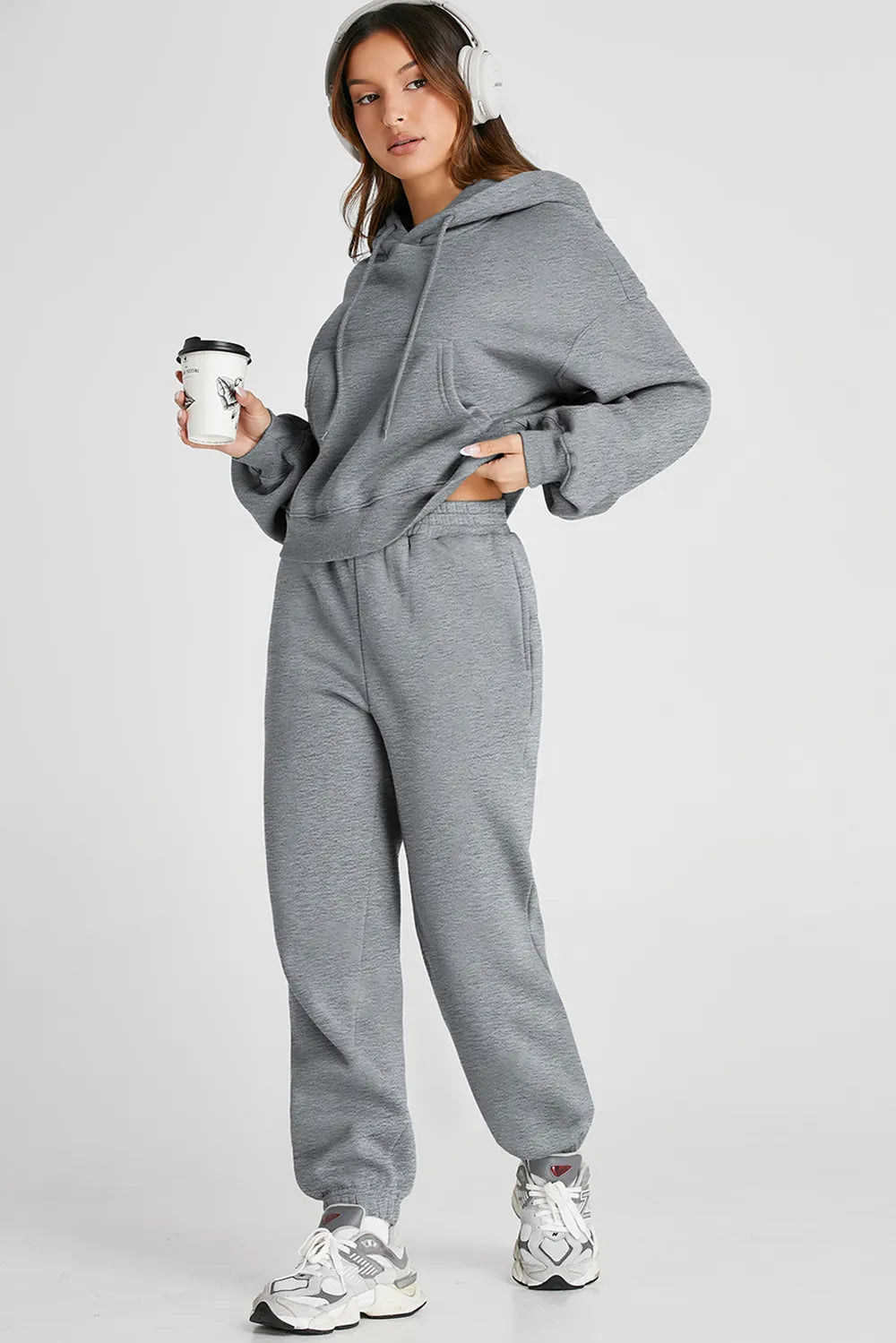 Woman wearing gray Dropped Shoulder Hooded Top and Pants Active Set with headphones and coffee cup
