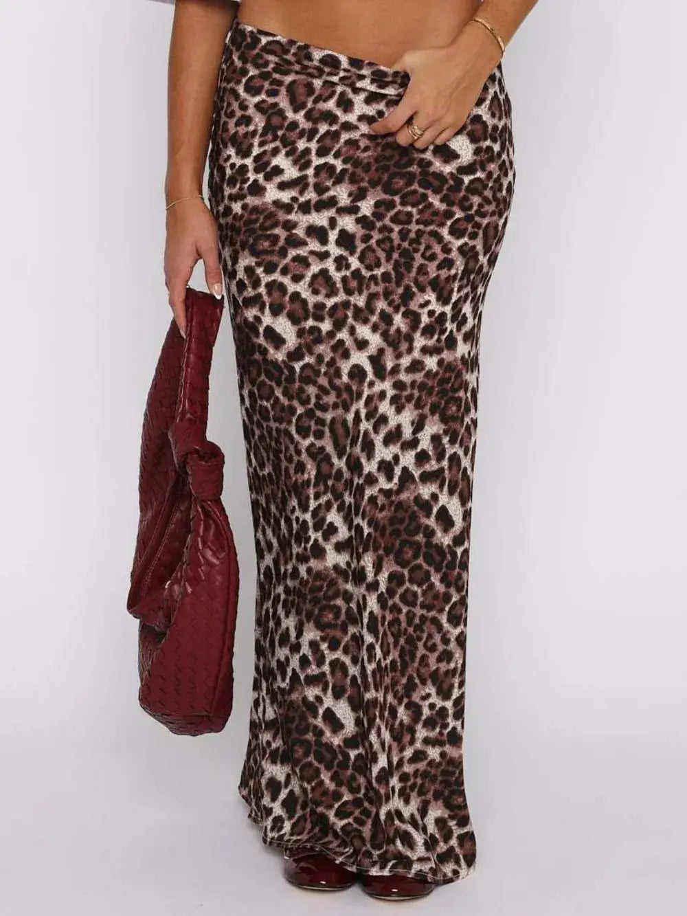 Woman wearing chic leopard print maxi skirt, holding a burgundy purse, perfect for glam or casual outfits.