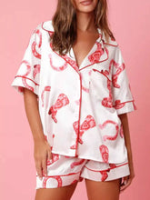 Model wearing Button Up Half Sleeve Shirt and Shorts Lounge Set with red-and-white festive print on pink background