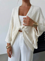 Woman wearing a twist-front textured knit cardigan in a soft, relaxed fit. Modern chic style with gold accessories.