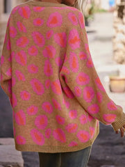 Woman wearing Leopard Oversized V-Neck Sweater with pink leopard print design on a tan background from GirlSavvi™. Cozy and stylish look.