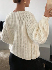 Back view of a white knit button-front cardigan with cozy texture, worn by a woman indoors.