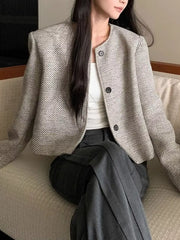 Woman wearing Tweed Cropped Jacket, buttoned, normal thickness, lined, made of 100% polyester, styled with grey trousers on a sofa.