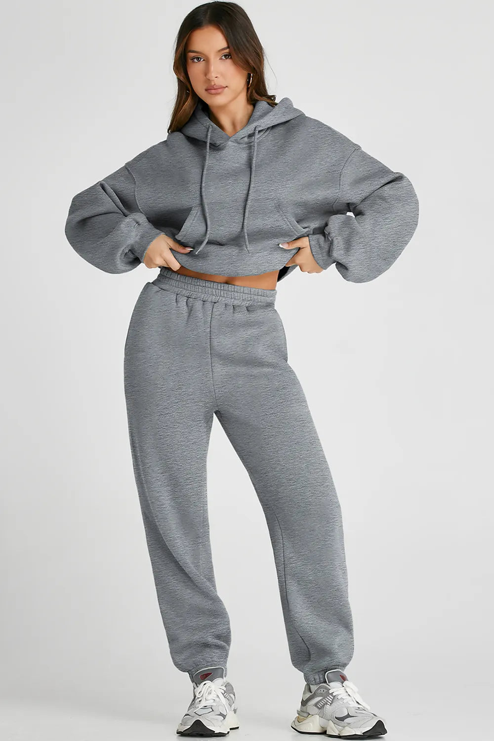 Woman wearing Dropped Shoulder Hooded Top and Pants Active Set in gray with drawstring and pockets.