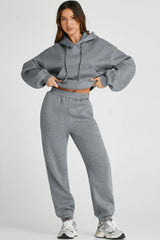 Woman wearing Dropped Shoulder Hooded Top and Pants Active Set in gray with drawstring and pockets.