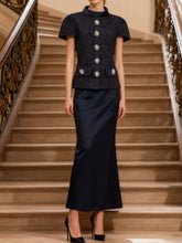 Elegant Tweed Jacket and Satin Skirt Set on staircase, featuring structured silhouette and statement buttons.