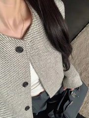 Woman wearing a buttoned Tweed Cropped Jacket with long sleeves, paired with a white top and carrying a black handbag.