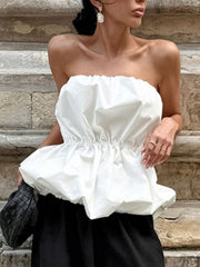 Woman wearing a white Ruched Bubble Hem Tube Top, featuring strapless design and ruched bodice, paired with black pants.