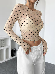 Woman wearing a Polka Dot Mesh Long Sleeve Crop Top with white pants for a chic and stylish look.