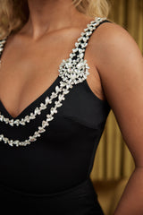 Close-up of a bodysuit with layered crystal stone straps, showcasing intricate detailing and shimmering accents against a dark fabric.