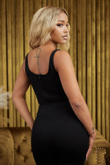 Model wearing a stylish black bodysuit with sleek structure against a golden background