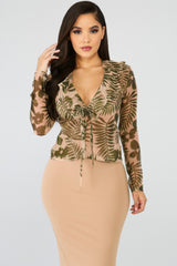 Model wearing leaf printed sheer blouse with long sleeves, front string tie, and ruffle accents, showcasing chic style and feminine elegance.
