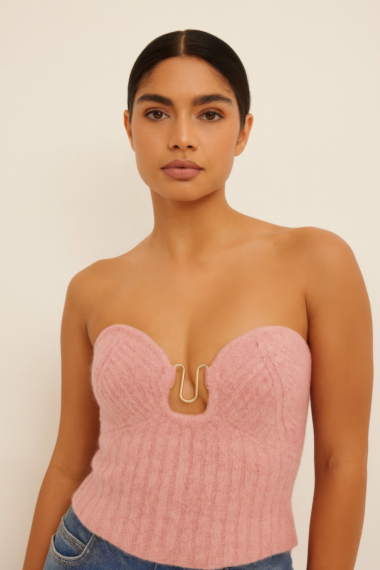 Model wearing pink knit tube top, chic and stylish design, strapless with front detailing, perfect for layering or solo wear.