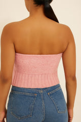 Back view of woman wearing pink knit tube top and denim jeans