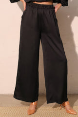 Woman wearing Modern Satin Pocket Pants with hammered satin texture and relaxed silhouette, featuring practical pockets for chicness.