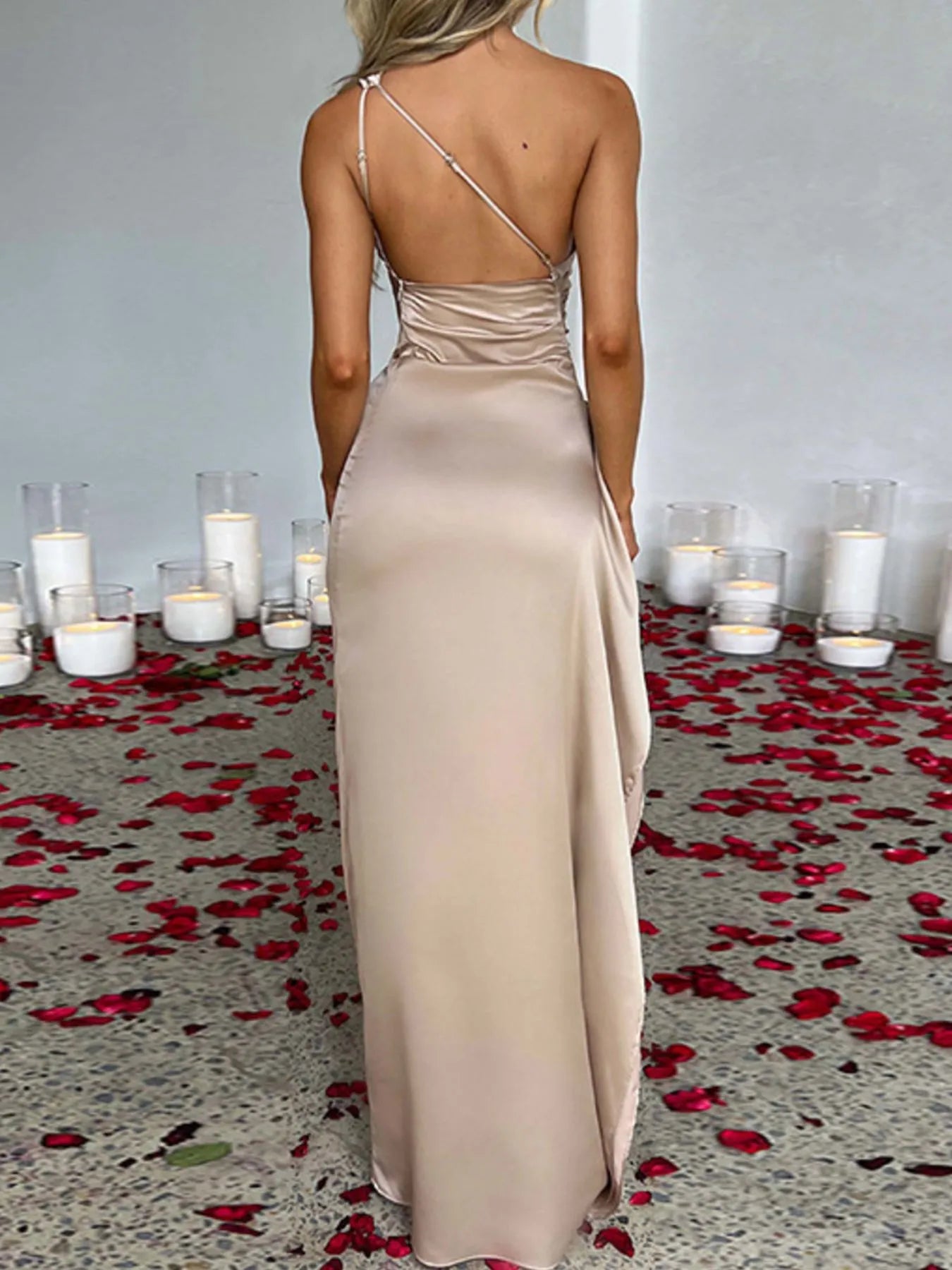 Back view of One Shoulder Satin Dress with High Slit, featuring ruched detailing and elegant satin finish, surrounded by rose petals.