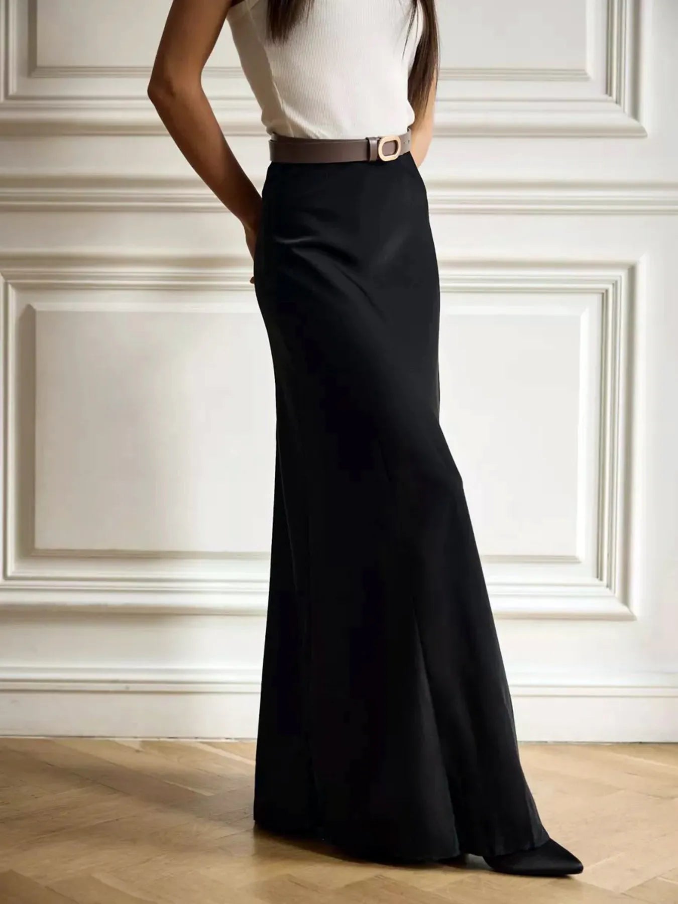 Woman wearing a black high-waisted maxi skirt made of 95% polyester and 5% spandex, showcasing a basic style without lining.