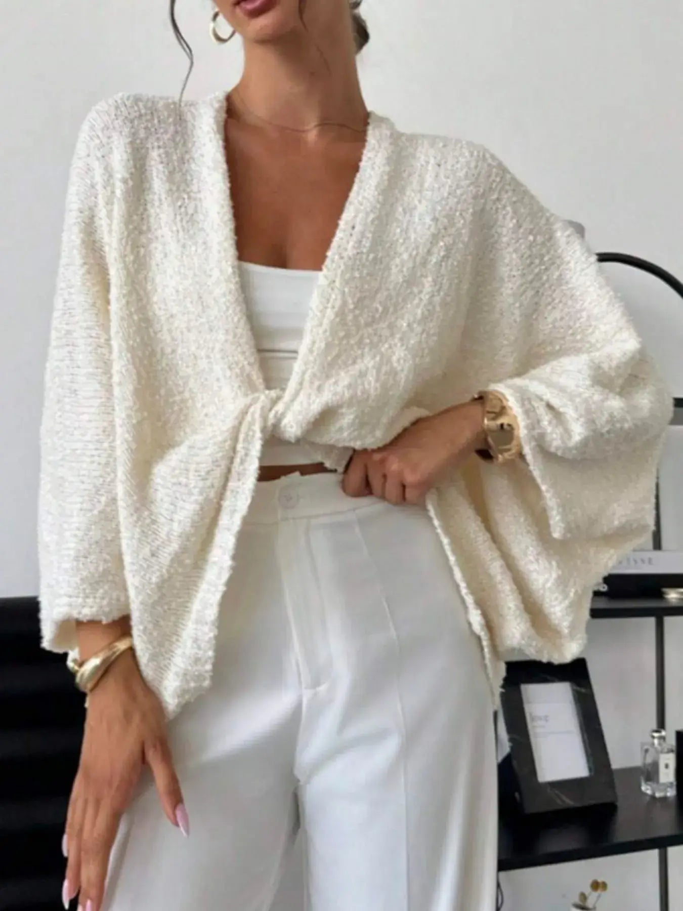 Woman wearing a Twist-Front Textured Knit Cardigan in white, paired with white pants for a modern chic look.