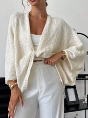 Woman wearing a Twist-Front Textured Knit Cardigan in white, paired with white pants for a modern chic look.