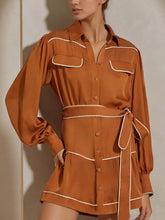 Model wearing Button Front Long Sleeve Shirt Dress in brown with belted waist and tiered design. Features buttoned front with no stretch.