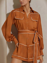 Model wearing Button Front Long Sleeve Shirt Dress in brown with belted waist and tiered design. Features buttoned front with no stretch.