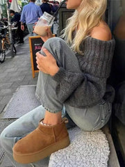 Woman wearing Off-Shoulder Ribbed Long Sleeve Sweater sitting casually in an urban setting