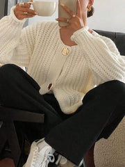 Woman wearing button-front knit cardigan with pockets, holding a cup. Cozy fashion style for casual outings.
