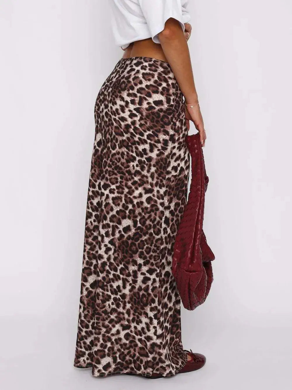Side view of a chic leopard print maxi skirt paired with a white top and red bag, showcasing a stylish and bold fashion look.
