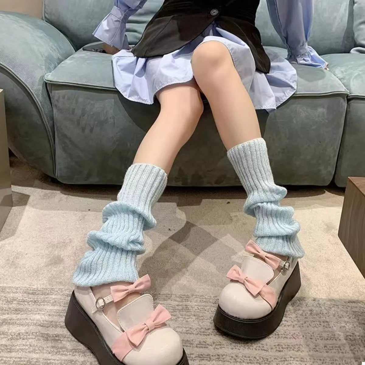 Woman wearing Ribbed Knit Leg Warmers with trendy shoes and skirt, showcasing a cozy winter look on a sofa.