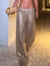 Woman wearing drawstring wide leg pants in shiny metallic fabric, showcasing a stylish summer look.