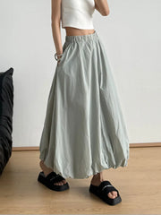 Woman wearing an elastic waist bubble hem maxi skirt with paperbag waist, showcasing casual style and comfort, in a modern setting.