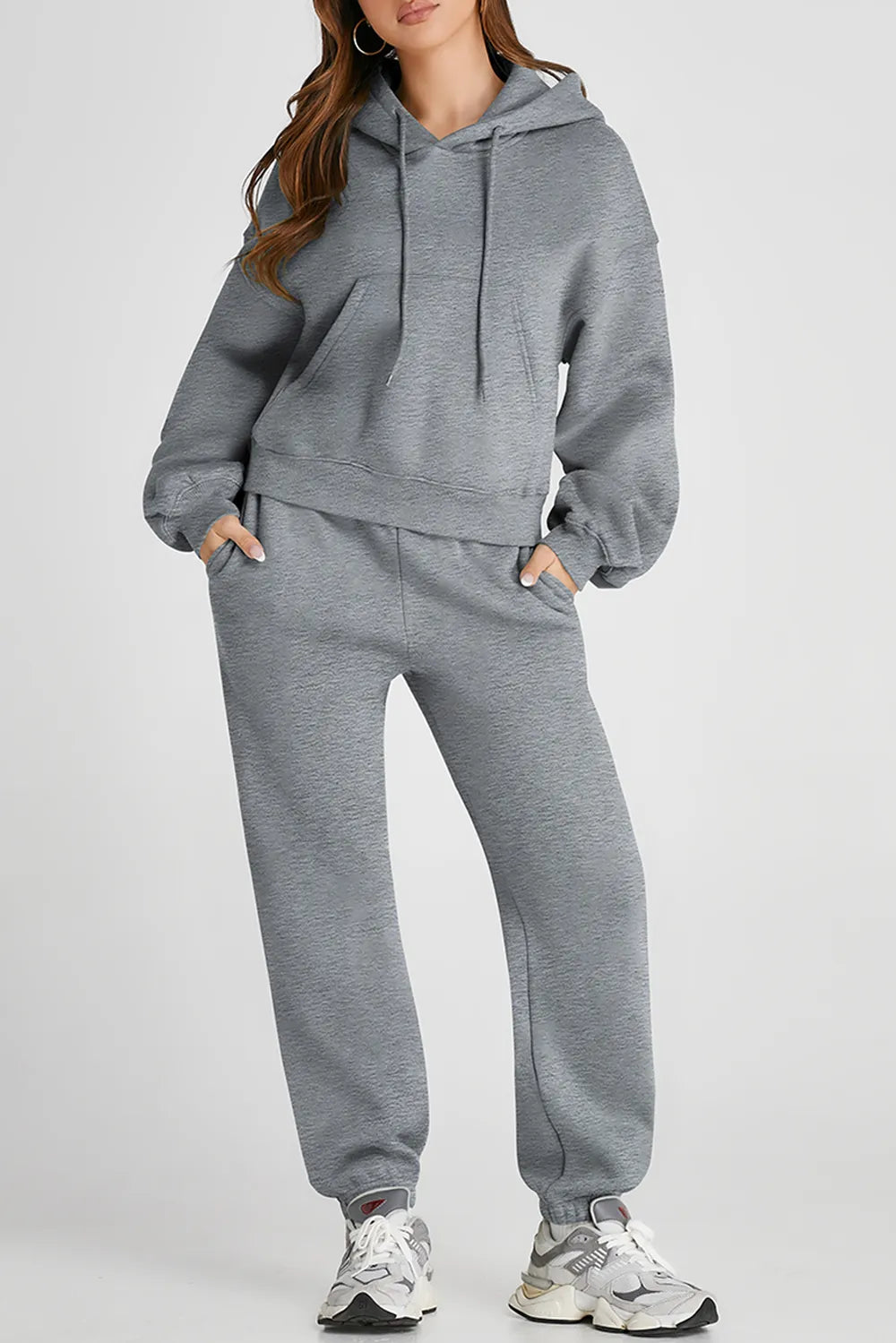 Woman wearing gray Dropped Shoulder Hooded Top and Pants Active Set with drawstring and pockets, made from polyester and cotton mix.
