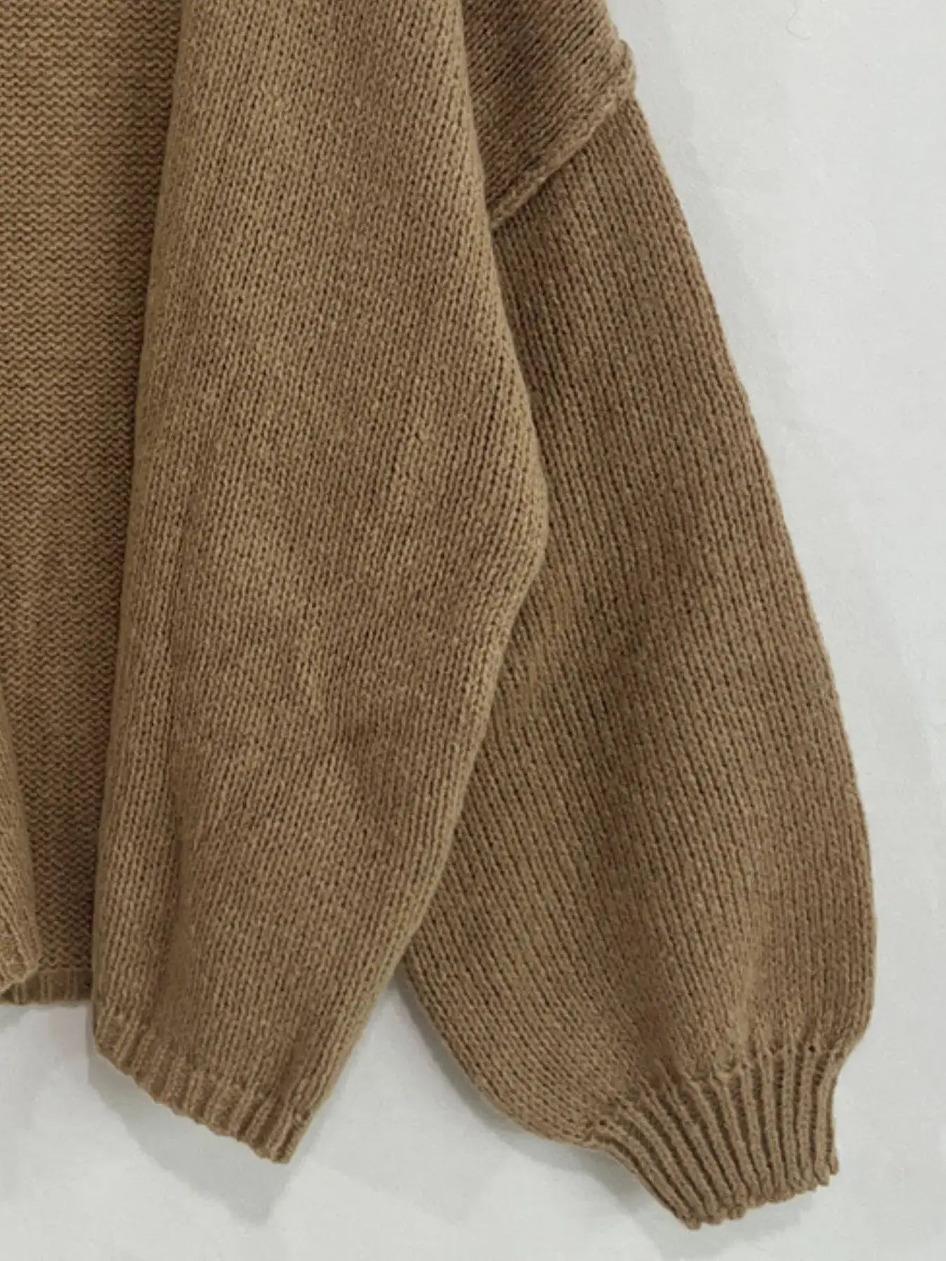 Close-up of oversized textured cardigan with dropped shoulder and voluminous sleeve in soft-touch brown polyester for chic layering.