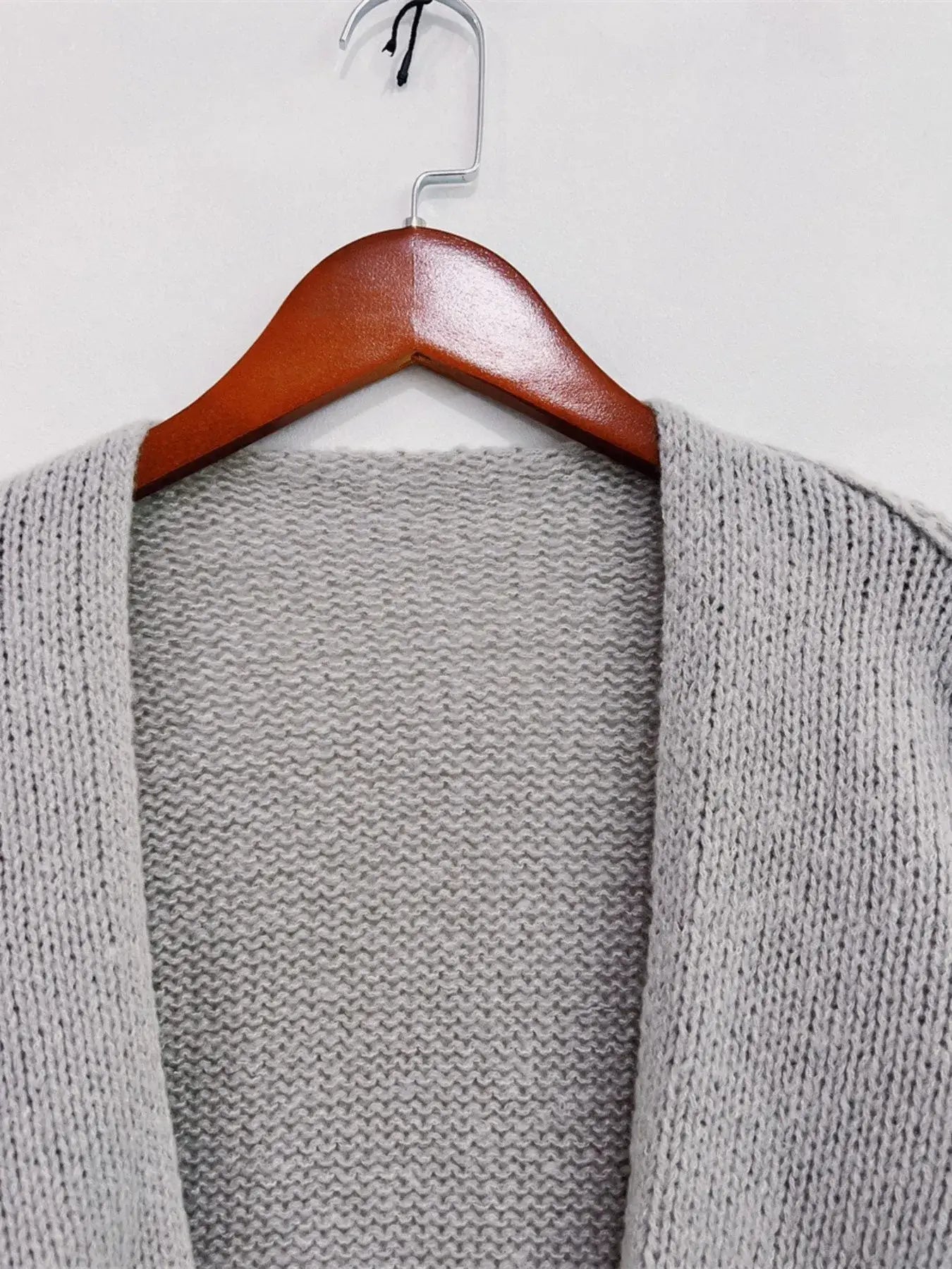 Gray oversized textured open front cardigan on wooden hanger, featuring dropped shoulders and soft-touch fabric for chic comfort.