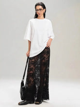 Model wearing a stylish lace maxi skirt with a white top, showcasing a chic and edgy fashion look.