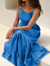 Model wearing a Tiered Maxi Cami Dress with Ruffled Hem in blue, showcasing its backless and tied design.