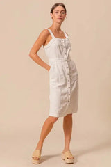 Lightweight cotton pinafore dress with button front and pockets, styled for a relaxed and timeless look.