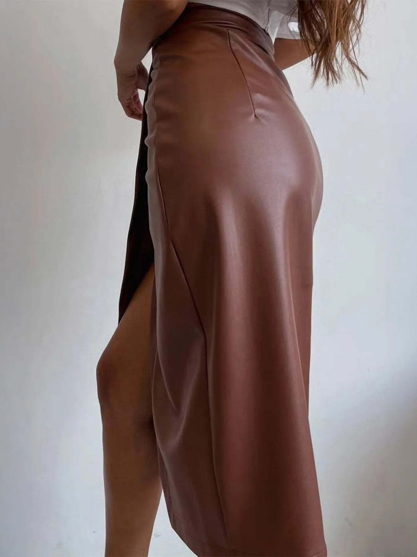 Woman wearing brown Slit Leather Midi Skirt with side slit, showcasing sleek and sophisticated style.