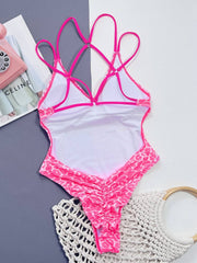 Backside of pink Leopard Plunge Swimwear laid flat, showing ruched detailing and strappy open back design.