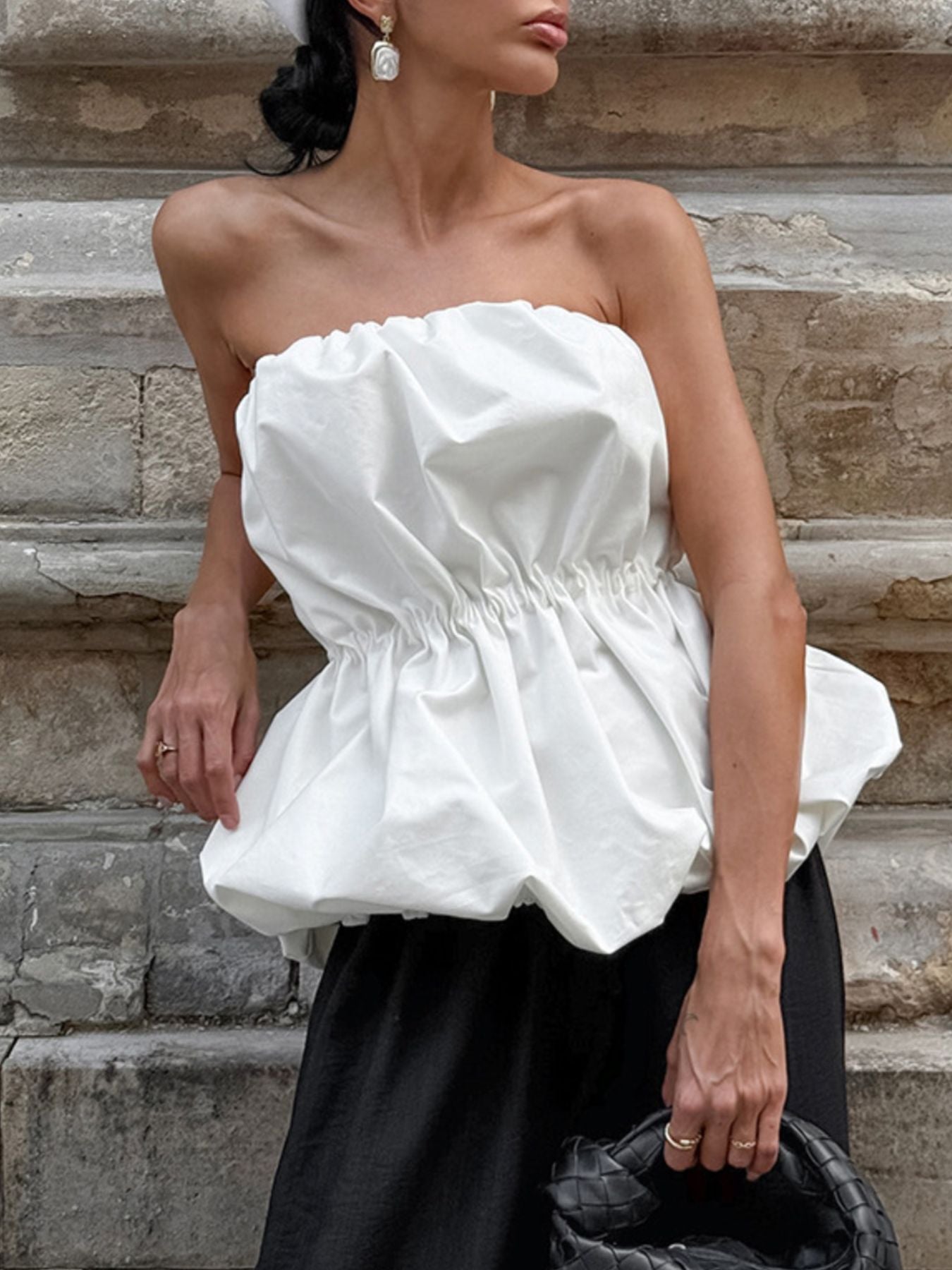 Woman wearing a white Ruched Bubble Hem Tube Top with elegant ruched bodice and voluminous bubble hem.