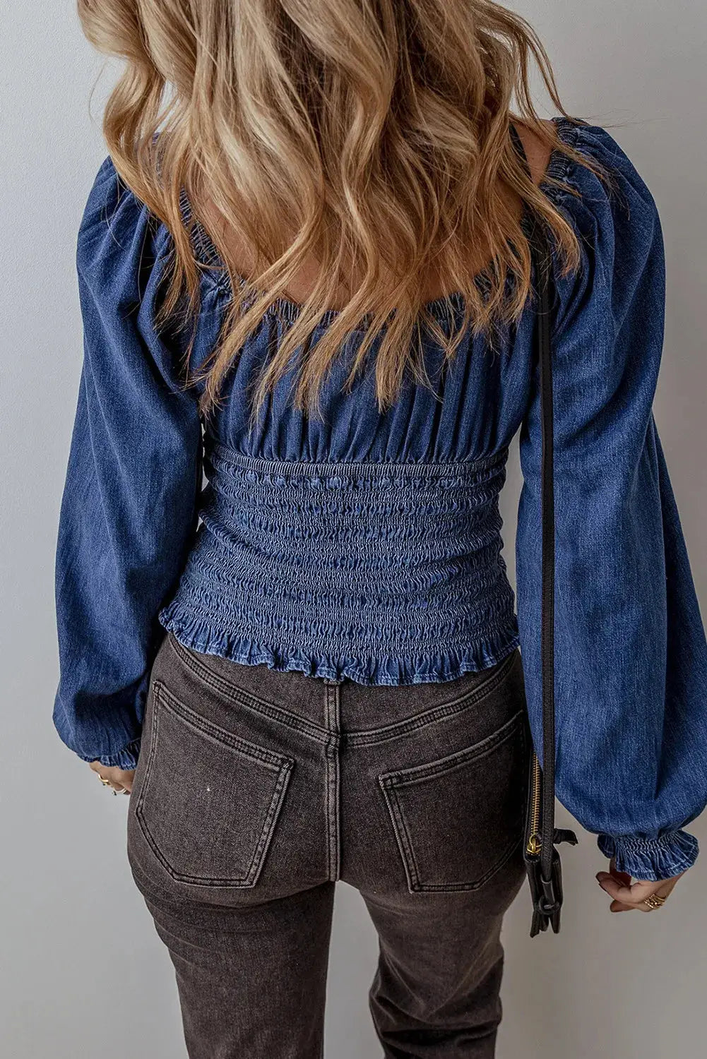 Back view of Smocked Long Sleeve Denim Top highlighting the cinched waist and ruffled hem, ideal for casual chic styling.