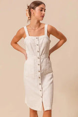 Classic cotton pinafore dress with button front and wide straps, ideal for layering in any season.