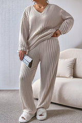 CurvyGirl Plus Size Ribbed V-Neck Drop Shoulder Top and Pants Set in neutral beige, styled with fluffy slippers for a comfortable loungewear look.