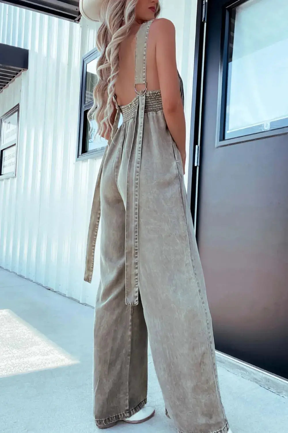 Side-back view of khaki V-Neck Sleeveless Denim Jumpsuit with adjustable straps and smocked back panel for flexible fit.
