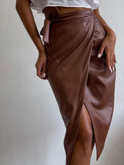 Model wearing Slit Leather Midi Skirt in brown with a front slit, showcasing sleek and sophisticated style.