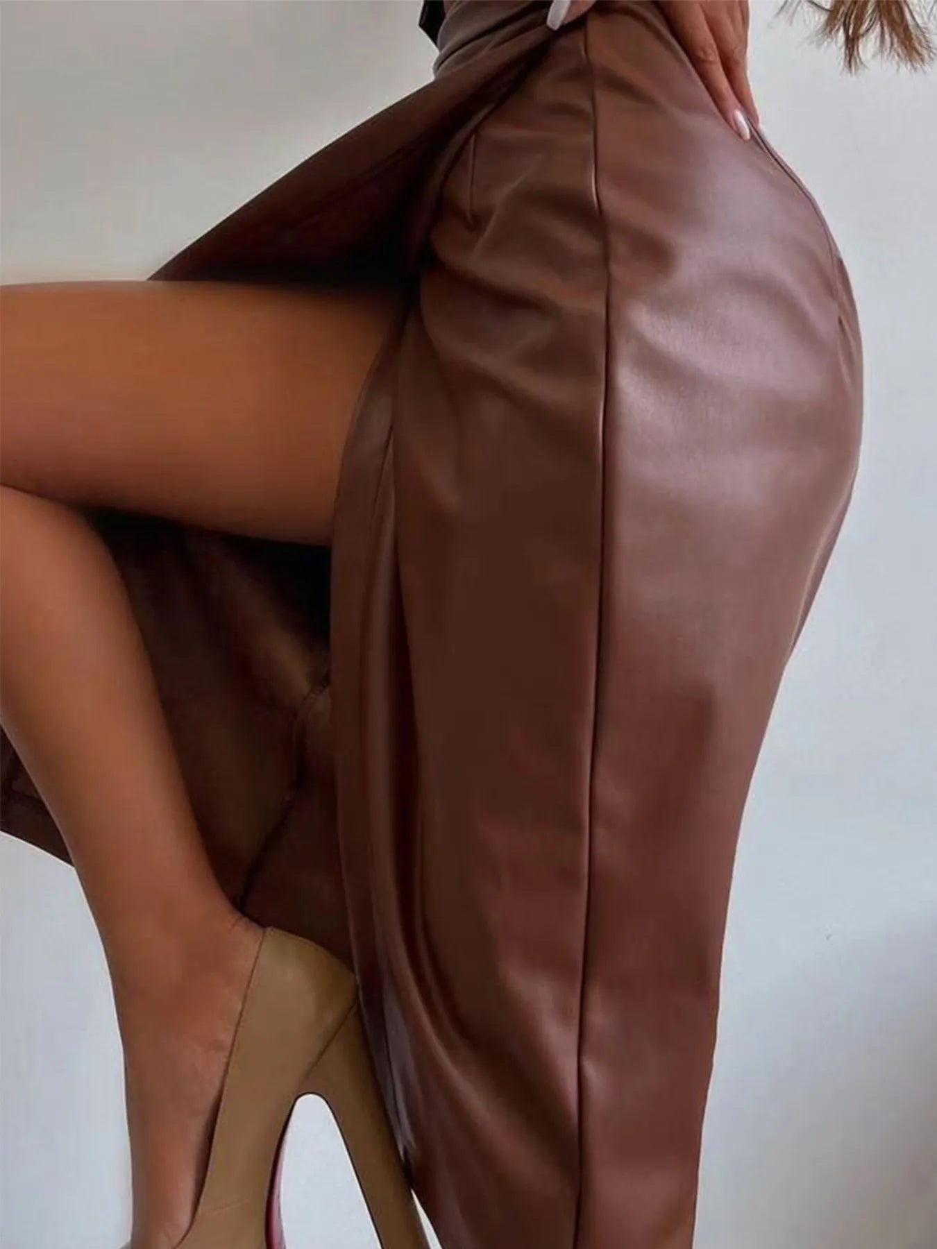 Side view of Slit Leather Midi Skirt showing front slit detail and smooth faux leather finish in sleek brown color.