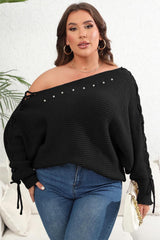 Plus Size One Shoulder Beaded Sweater in black with long sleeves and tied detailing, styled casually with jeans for curvy women. Features silver bead accents along neckline.