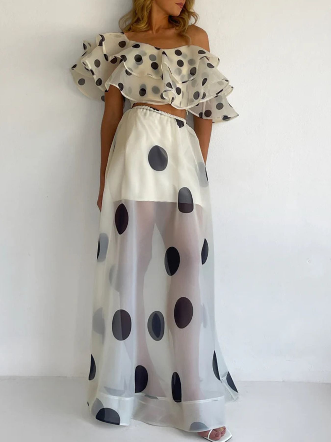 Woman wearing a Polka Dot Ruffle Crop Top and Maxi Skirt Set, featuring an off-shoulder design with a flowing high-waisted skirt.